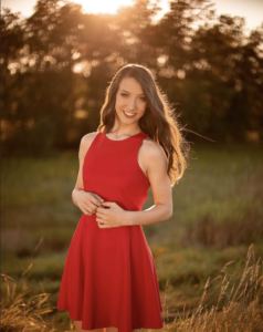 A woman in a red dress smiling.